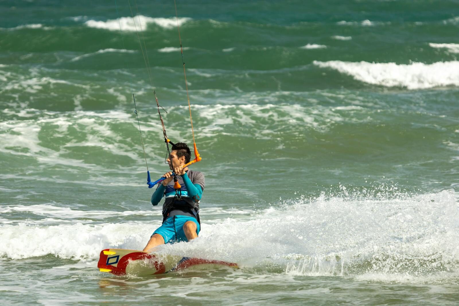 A man enjoys kiteboarding in the ocean, creating splashes and thrills on a sunny day.
